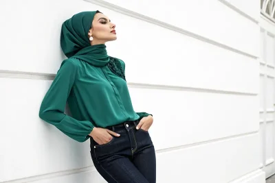 زن با پوست روشن با لباس سبز زمردی و شلوار جین تیره