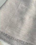 نمای نزدیک از بافت شال کریشه تابستونی در رنگ طوسی نقره‌ای روشن، با خطوط ظریف و بافت نرم به همراه لبه‌های ریش‌ریش، مناسب برای استایل‌های تابستانی و روزمره
