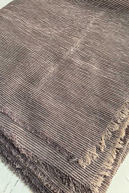 تصویر نمای نزدیک از بافت شال کریشه تابستونی با رنگ قهوه‌ای تاپی، دارای بافت ریز راه‌دار و لبه‌های ریش‌ریش، مناسب فصل تابستان